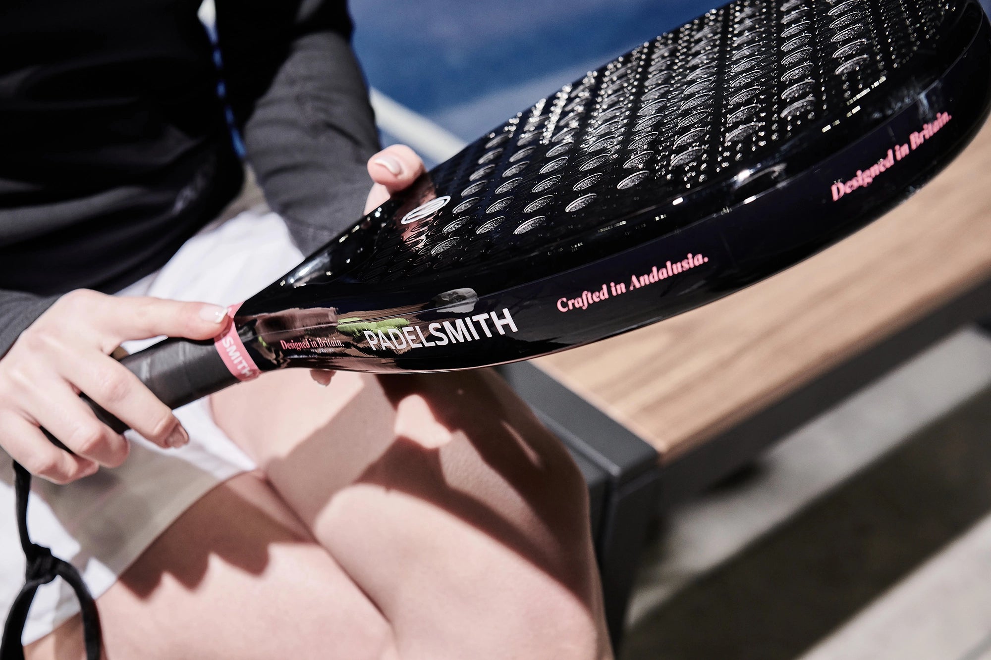 Close-up of hands holding the Padelsmith #1 padel racket showing 'Designed in Britain, Crafted in Andalusia' branding