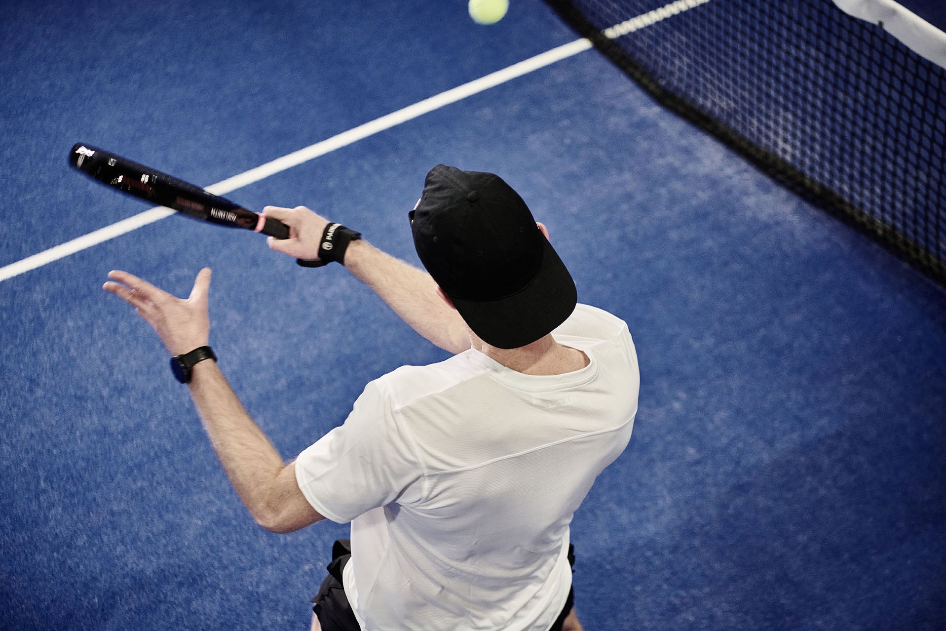 Overhead view of a player smashing with the Padelsmith #1 padel racket on a blue court