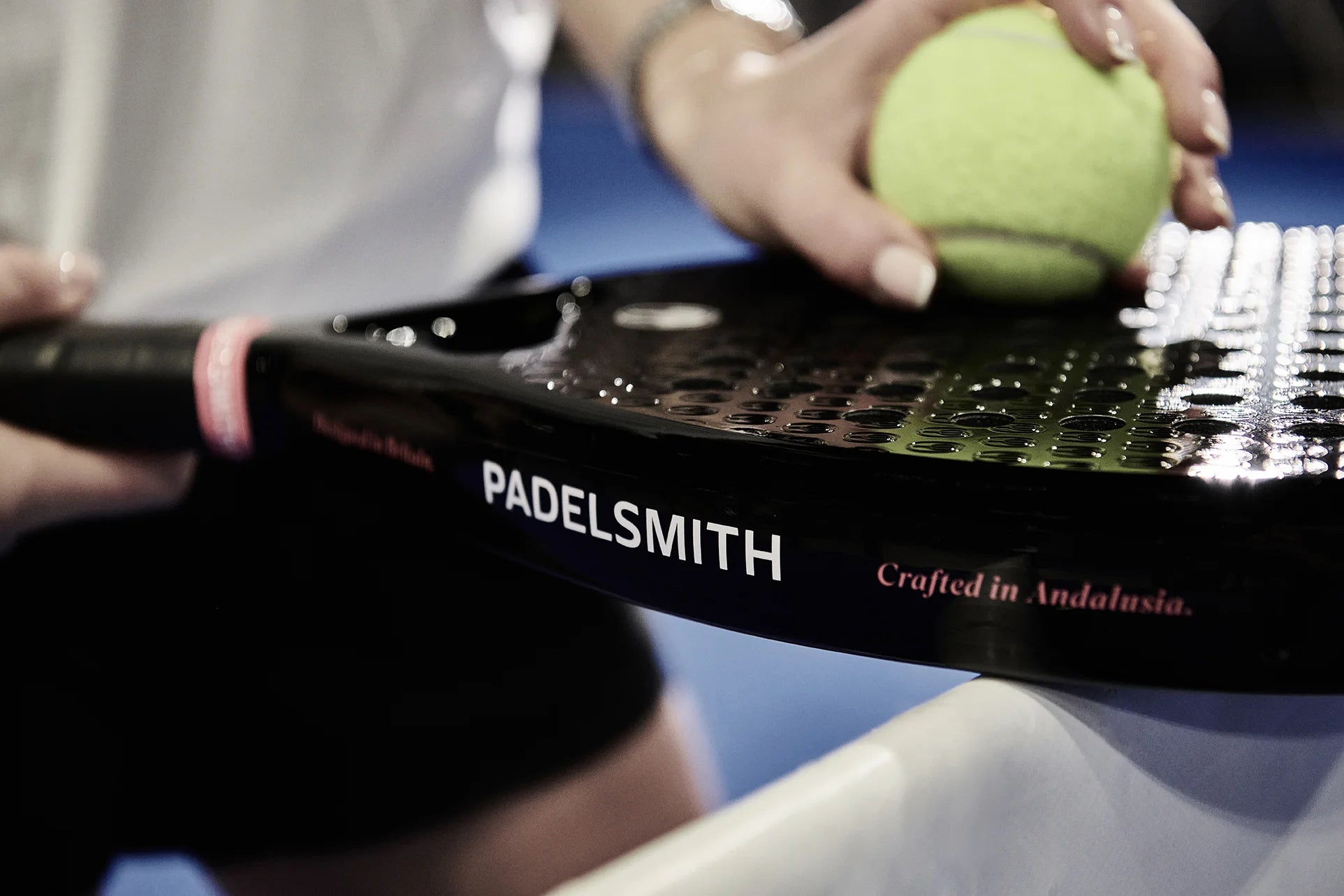 Close-up of a padel player holding the Padelsmith #1 racket near a ball, with Crafted in Andalusia branding visible