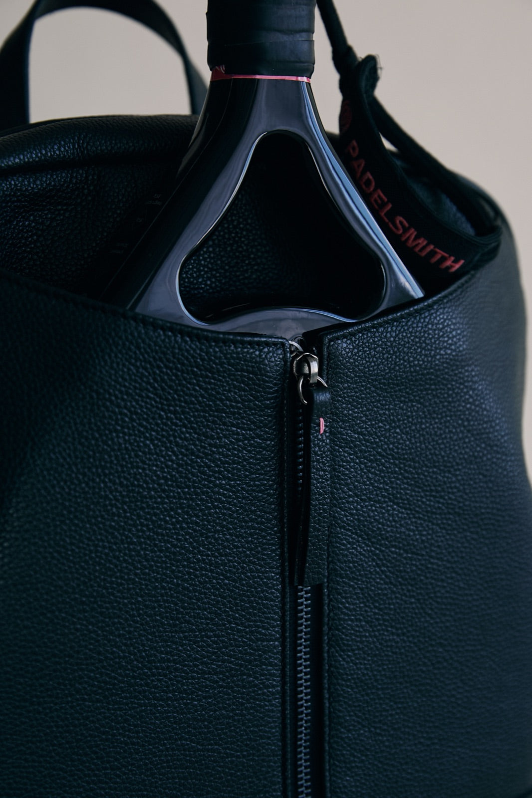 A Padelsmith racket in the front pouch of The Padelsmith Bag, close up of the leather grain and zip